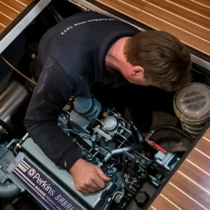 Mecánico revisando motor en compartimento de barco.