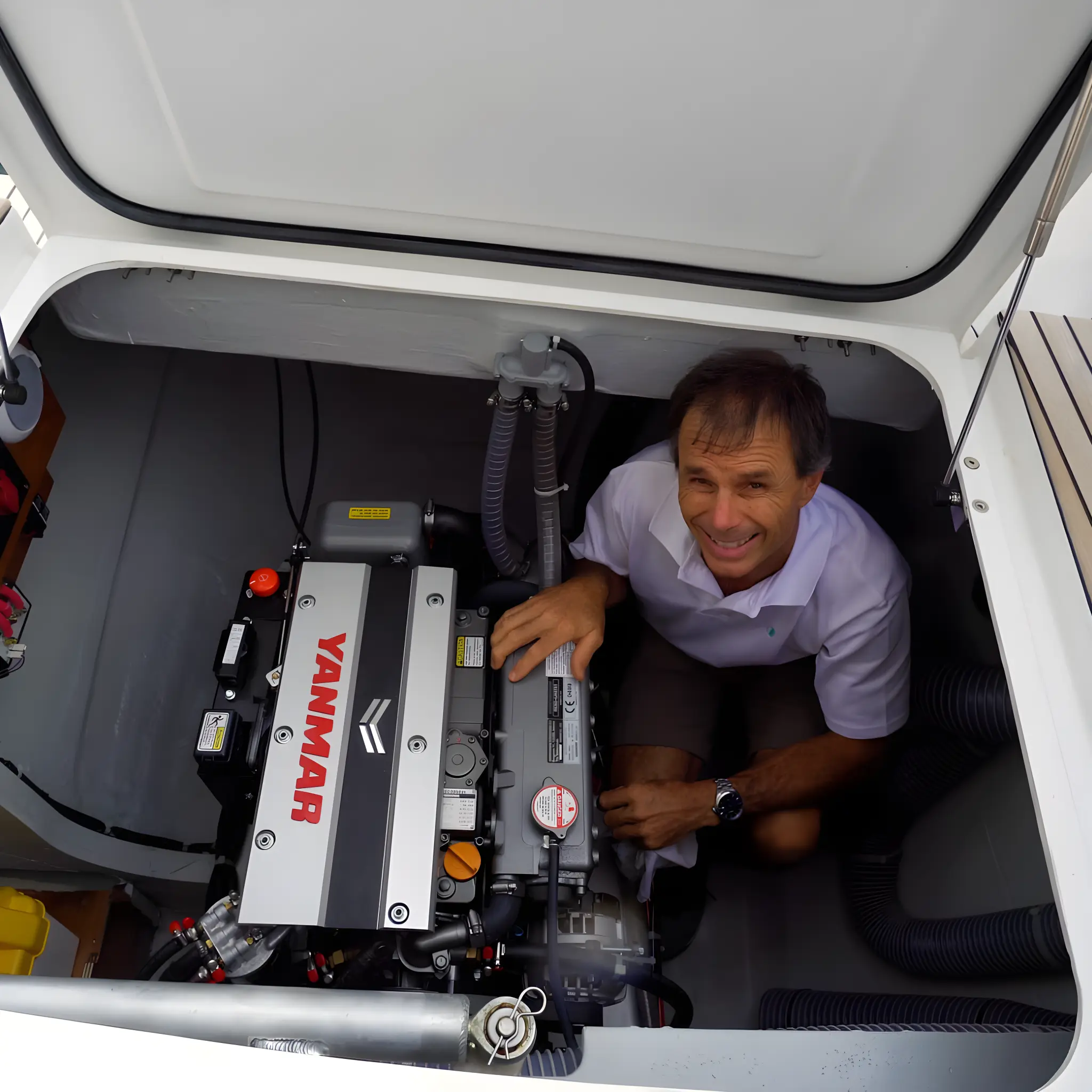 Mantenimiento de barcos en Barcelona 6 Hombre sonriente revisando motor en compartimento de barco.