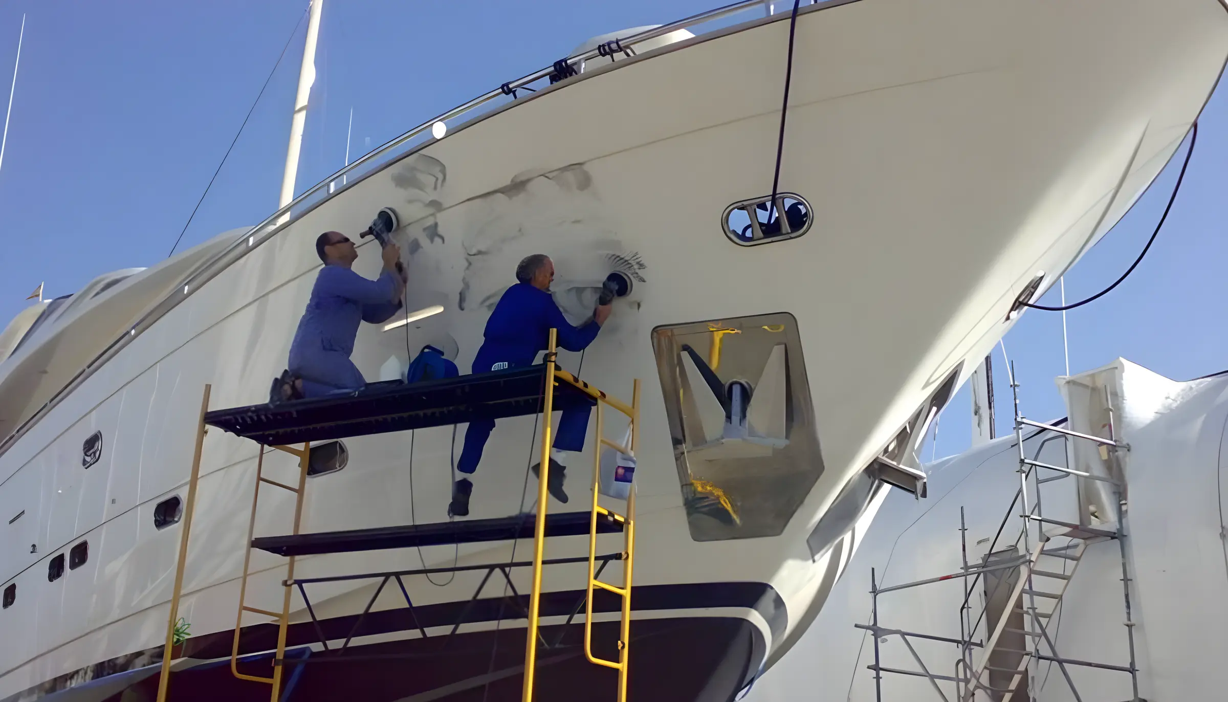 Trabajadores reparando casco de yate sobre andamios